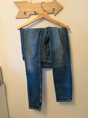 Blå raka jeans från GANT - Säljer ett par blå jeans från GANT med rak passform och klassisk femficksdesign. Jeansen har marinblåa tvätt med lätt slitning och är tillverkade i denim.