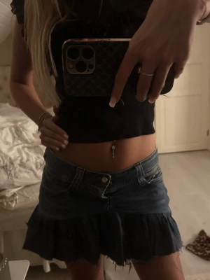 Mörkblå jeanskjol med volang - Säljer en mörkblå jeanskjol från miss sixty  med volangkant och råa kanter. Kjolen har klassiska jeansdetaljer som fickor och bälteshällor. Perfekt för dig som vill ha en trendig och edgy look.