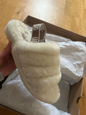 Fluffiga sandaler från UGG - Säljer ett par supermjuka och fluffiga sandaler från UGG i krämvit färg. Hel nya har endast går ut med dom i mindre än 5 minuter annars helt nya i storlek 39 ( köparen står för frakt om det ska skickas)