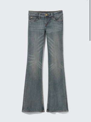 Cheap Monday jeans - OANVÄNDA med lappen kvar! Snygga blå bootcut jeans med lätt slitna detaljer och klassisk femficksdesign. Jeansen har låg midja, utsvängda ben och dekorativa sömmar. Perfekta för en avslappnad och trendig look.