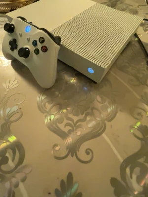 Xbox One S vit spelkonsol - Vit Xbox One S funkar helt okej  handkontroll med klassisk design och svarta detaljer. Ergonomisk form med greppvänliga ytor och färgade knappar. Perfekt för gaming och kompatibel med Xbox One S. Materialet är plast med matt finish. 