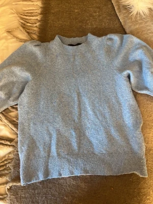 Ljusblå puffärm stickad tröja Vero Moda💕 - Supersöt ljusblå stickad tröja från Vero Moda med puffärmar och ribbade muddar vid hals, ärmslut och nederkant. Perfekt för dig som vill ha en trendig och mysig look. Materialet känns mjukt och behagligt mot huden.