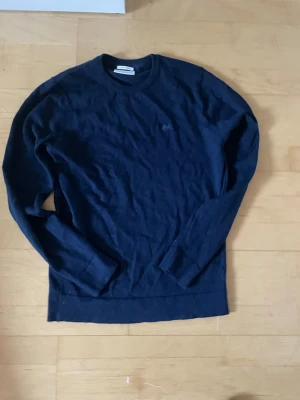 Mörkblå merinoullströja Lindbergh - Snygg mörkblå stickad tröja från Lindbergh i slim fit-modell. Tillverkad i mjuk merinoull som känns lyxig och skön mot huden. Klassisk rund halsringning och långa ärmar, perfekt för lager på lager under kyliga dagar. Men även under en lite kyligare sommar kväll. 