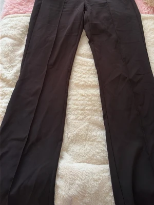Svarta kostymbyxor med raka ben - Snygga svarta kostymbyxor med klassisk rak passform och pressveck. Perfekta för en stilren look. Byxorna har hög midja och är tillverkade i ett mjukt, vävt tyg som ger en dressad känsla.