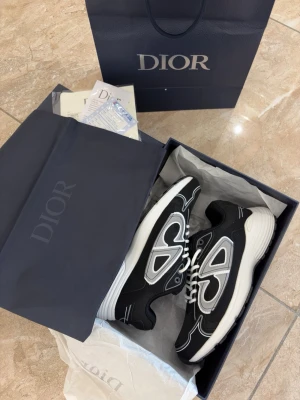 Svart silver B30 - Snygga svarta b30 sneakers med vita och grå detaljer samt vita skosnören. Skorna har en chunky vit sula och meshpaneler för extra komfort. Märkeslogga på plösen och cool design som sticker ut. Perfekta för dig som vill ha en exklusiv och trendig look.