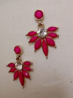 Rosa statementörhängen med strass - Snygga örhängen i guldtonad metall med klara strasstenar i mitten och rosa bladformade detaljer runt om. Örhängena har en unik och trendig design som verkligen sticker ut. Perfekta för att ge din outfit en färgklick och extra bling.