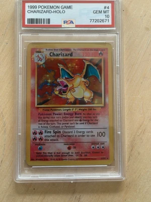 Charizard Pokémonkort PSA 10 - Skick enligt bilder. Säljer ett sällsynt Charizard Holo-kort från 1999 Pokémon Game, graderat PSA 10 GEM MT. Kortet är inneslutet i en genomskinlig plastkapsel med PSA-märkning. Perfekt för samlare som vill ha en ikonisk och klassisk Pokémon i toppskick.