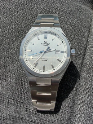 Casio Edifice EFB-108D-7AVUEF (Safirglas / Full Set) - Säljer en riktigt stilren och välvårdad Casio Edifice (modell: EFB-108D-7AVUEF). En fantastisk "everyday watch" i sportstål-design med integrerad länk som passar till allt från vardag till fest. Klockan är känd för sin otroligt tunna profil (endast ca 7,8 mm), vilket gör att den sitter väldigt bekvämt på handleden. Den ljusa urtavlan har en supersnygg vertikal borstning och en ljusblå sekundvisare som ger en fin färgklick. Höjdpunkter: • Repfritt safirglas – håller klockan fräsch i alla lägen. •