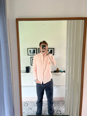Ljusrosa Linneskjorta - Säljer en stilren ljusrosa linneskjorta med klassisk krage och knäppning framtill. Skjortan har lång ärm och en relaxed passform som passar perfekt till jeans eller chinos. Enkel och fräsch look för dig som gillar minimalistisk stil.