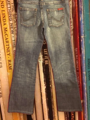 Blå bootcut jeans från ONLY - Snygga blå bootcut jeans från ONLY med klassisk femficksdesign och slitna detaljer. Jeansen har en lätt tvättad look och röda ONLY-loggan på bakfickan. Perfekta för en avslappnad och trendig stil.