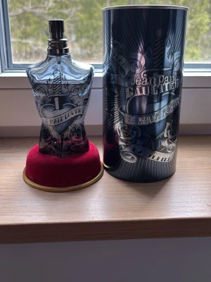 Jean Paul Gaultier Le Male Lover EdP LIMITED - Jean Paul Gaultier Le Male Lover Eau de Parfum i en unik flaska formad som en manlig torso med tatueringsinspirerad design i svart och silver. Kommer med original metalltub och röd sammetsbas. Volym: 125 ml. Perfekt för dig som gillar ikoniska dofter.
