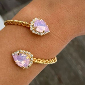 Armband Bangle  - Armband, Bangle, i guldpläterad mässing med kristaller. Kristaller Pear 14mm, Färg Rose Water Opal. Kristaller i Clear Crystal Runt om. Ställbar storlek. De senare bilderna andra armband som finns i lager. Jag skickar endast spårbart, samfraktar. Fast pris. Besök gärna mina övriga annonser.  Till mina smycken använder jag kristaller från Preciosa, Aurora och Swarowski.