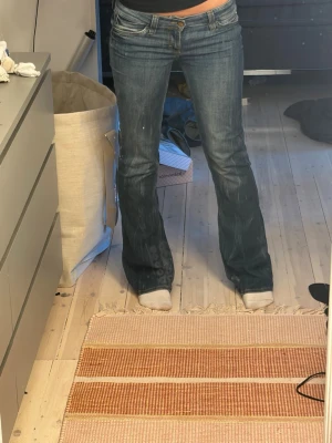 Jeans  - Snygga blå bootcut-jeans från weekday med låg midja och klassisk femficksdesign. Jeansen har gröna detaljer och en grön patch bak i midjan. Tillverkade i denim med lätt slitning för en cool look.