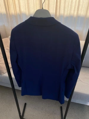 Mörkblå kostym med kavaj och byxor - Säljer en stilren mörkblå kostym med klassisk kavaj och matchande byxor. Perfekt för dig som vill ha en enkel och snygg look. Kostymen har en slim fit passform och är tillverkad i ett slätt material. Köpt på dressmann, använd en gång. Byxorna är i storlek 30/30 och kavajen är i storlek 44R slim fit. 