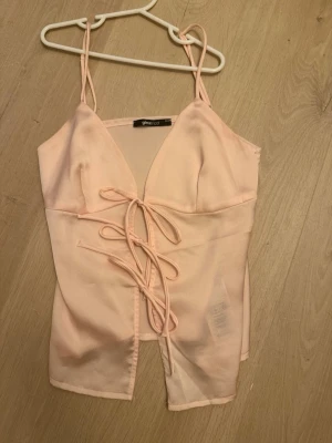 Ljusrosa linnetopp med snörning -  ljusrosa linnetopp från Gina Tricot med smala axelband och snygg snörning framtill