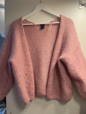 Rosa fluffig stickad tröja Lindex - Mysig rosa stickad tröja från Lindex i storlek XS/S. Tröjan har en fluffig och mjuk känsla, rund halsringning och långa ärmar. Perfekt för att hålla värmen under kyliga dagar och ger en söt och trendig look.