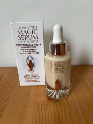 Charlotte Tilbury Magic Serum Elixir - Charlotte Tilbury Magic Serum Crystal Elixir är ett lystergivande serum med vitamin C, niacinamid och peptider. Kommer i en genomskinlig glasflaska med pipett och har en ljus, krämig färg. Perfekt för dig som vill boosta huden med glow. Oöppnad såklart, nypris 939kr
