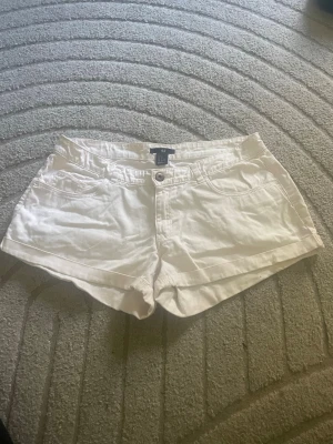 ljusrosa shorts från H&M med fickor - Snygga ljusrosa shorts från H&M med klassisk femficksdesign och uppvikta benslut. De har normal passform och stängs med knapp och dragkedja. Perfekta för varma dagar och enkla att matcha med allt. Materialet är mjuk bomull som känns skönt mot huden.