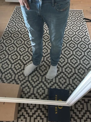Ljusblå jeans från Diesel - Säljer ett par ljusblå skinny jeans från Diesel med låg midja och smal passform. Jeansen har klassisk femficksdesign och är tillverkade i en stretchig tunnare bomullsblandning för extra komfort. Perfekta för dig som gillar en modern look. Den har en justerbar midja och passar ca w27, w28 +/- de är i mycket bra skick.