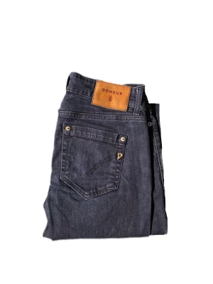 Blå jeans från Dondup - Snygga blå jeans från Dondup med klassisk femficksdesign och brunt läderpatch på bakfickan. Jeansen har raka ben och är tillverkade i denim med metallnitar och diskret D-logga på fickan. Perfekt för dig som gillar stilrena och tidlösa jeans.