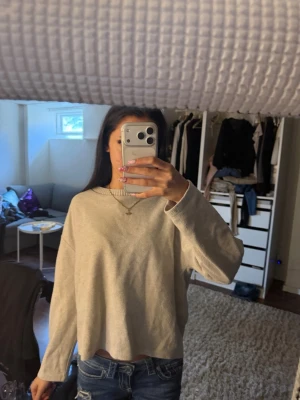 Beige oversized tröja - En beige oversized tröja med rund halsringning och långa ärmar. Tröjan har en enkel och avslappnad passform, perfekt att styla med jeans. Materialet ser ut att vara mjukt och bekvämt, troligen bomull eller bomullsblandning.