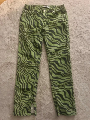NA-KD jeans - 💚 NA-KD gröna mönstrade jeans – trendiga & unika 💚  Beskrivning: Supercoola gröna jeans från NA-KD med vågigt mönster som verkligen sticker ut 🔥 Perfekta för dig som vill ha en statement-look – funkar lika bra till vardag som festival/outfit med edge.  ✔ Trendigt grönt print ✔ Skön passform ✔ Klassisk jeansmodell med fickor ✔ I fint skick, sparsamt använda  Säljs eftersom de tyvärr inte kommer till användning.