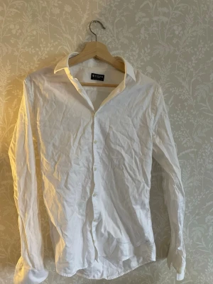 Vit skjorta från Tiger of Sweden - Klassisk vit skjorta från Tiger of Sweden i extra slim passform. Skjortan har långa ärmar, knappar framtill och en stilren krage. Perfekt för dig som gillar en clean och tidlös look.