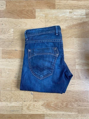 Mörkblå smått flared jeans - Snygga mörkblå jeans med lite flared/bootcut ben och klassiska kontrastsömmar. Jeansen har fem fickor och en enkel design utan synligt märke. Perfekta för en avslappnad och stilren look.