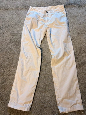 Vita chinos från Massimo Dutti - Snygga beiga chinos från Massimo Dutti i klassisk rak modell. Byxorna har normal midja, knapp- och dragkedjestängning samt diskreta fickor. Perfekta för en stilren och avslappnad look. Tillverkade i mjukt bomullstyg för extra komfort.