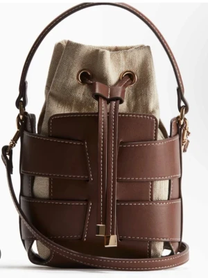 Brun bucket bag med canvasdetaljer - Snygg bucket bag i brunt läder från Hm. Väskan har tyvärr ingen gullig detalj på ena bandet längst ned då den var borta redan när jag köpte den i butiken.