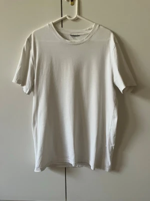 Vit basic t-shirt i premium bomull H&M strl XS - En klassisk vit t-shirt från H&M med rund hals och korta ärmar. Tillverkad i premium bomull ”Premium Cotton” vilket är högsta kvalité på H&M’s tröjor. Storlek XS. Material 100% bomull. Etikett för märke, storlek och material är klippta.