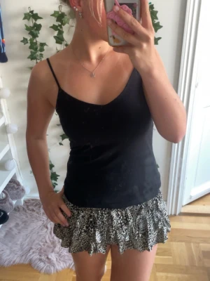Leopardmönstrad volangskjol - Säljer en leopardmönstrad skjol med volanger och hög midja. Skjolen har en elastisk midja som ger en bekväm passform och ett flowy fall. Perfekta för dig som vill sticka ut med ett djuriskt mönster och trendig look.