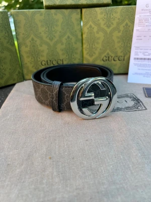 Svart Gg bälte med GG-spänne - Snyggt svart bälte från Gg med klassiskt GG-mönster och ett stort, silverfärgat GG-spänne. Bältet är gjort i skinn och har en stilren design som lyfter vilken outfit som helst. Perfekt accessoar för dig som gillar exklusiva detaljer.