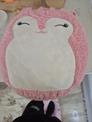 Rosa Squishmallows kudde igelkott - Supermjuk och fluffig kudde från Squishmallows formad som en igelkott. Kudden är rosa med vit mage, har broderat ansikte och öron samt en fluffig blå och lila taggig rygg. Perfekt som mysig inredningsdetalj eller gosedjur.