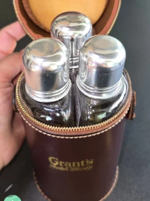 Grant's whiskykit med tre glasflaskor - Säljer ett klassiskt whiskykit från Grant's med tre glasflaskor och tillhörande brunt fodral i läder med dragkedja. Flaskorna har silvriga metallock och fodralet har Grant's-logga i guld. Perfekt för utflykter eller samling.