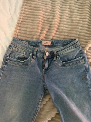 Blå bootcut jeans från LTB  - Säljer ett par klassiska blå bootcut jeans från LTB med fem fickor och normal midja. Jeansen har en snygg tvätt med lätt slitning på låren och raka ben som går ut lite nedtill. Perfekta till sneakers eller boots för en avslappnad look. Storlek 27/34