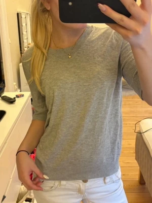 Ljusgrå basic topp med kort ärm - En enkel och stilren ljusgrå tröja med rund hals och korta ärmar. Tröjan har en rak passform och är tillverkad i ett mjukt, tunt material som känns skönt mot huden. Perfekt att matcha med jeans eller kjol för en clean look🙌🏼🤩