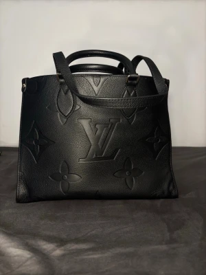 Svart Louis Vuitton handväska i läder - Säljer en svart handväska från Louis Vuitton i präglat läder med klassiskt LV-monogram och blommönster. Väskan har både handtag och axelrem för olika stilar. Snygg och rymlig modell som passar perfekt till din outfit. Den är modellkoden M45321 jag är öppen för pris några frågar kan sicka mer bilder 