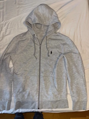 Ljusgrå zip hoodie från Polo Ralph Lauren - Snygg ljusgrå hoodie med dragkedja från Polo Ralph Lauren. Den har tecken på användning (bild 3). Storlek S.