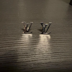 Silvriga örhängen  - Helt nya, silvriga örhängen. Pinne med plopp baktill. Ca 1.3 cm på höjden. Finns matchande armband till. Vill man köpa dom tillsammans, kan jag göra bättre pris. Såklart oanvända!