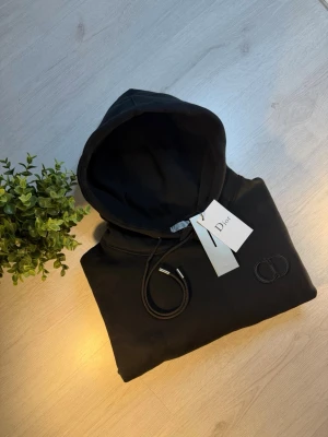 CD Hoodie - CD Hoodie - Storlek: S (enligt etikett).   - Stor i storleken och motsvarar ungefär M  - Mått:   - Längd: ca 66 cm   - Bredd (armhåla till armhåla): ca 55 cm   - Fint skick. Säljes då den är för stor för mig. 📏  - Skick: 10/10♻️   - Pris: 1300kr💵   - Färg: Svart - Frakt: Fraktas samma dag, anländer till dig inom 3-4 dagar🚚   Tveka inte att skriva vid minsta fråga!💭
