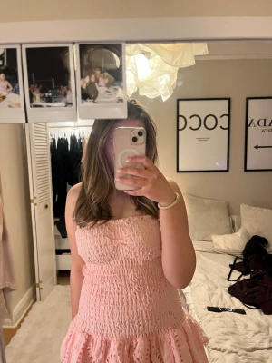 Ljusrosa klänning med volang - Jättesöt klänning med volanger från Design by Amore. Den är väldigt stretchig och perfekt till skolavslutning. Använt få gånger. 