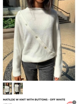 Offwhite stickad tröja med knappar - Säljer en offwhite stickad tröja med dekorativa knappar diagonalt framtill. Tröjan har rund hals, långa ärmar och ribbade muddar. Perfekt för dig som gillar stilrena och trendiga plagg med en twist. Kontakta mig för flera bilder!