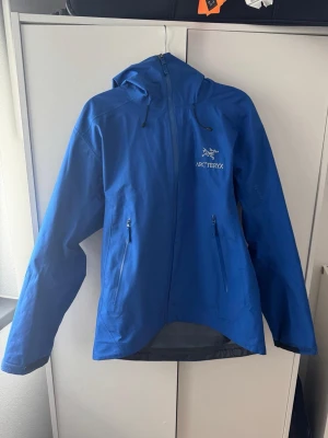 Blå skaljacka från Arc'teryx - Gore-tex skaljacka från Arcteryx som använd fåtal gånger under min skidsäsong, därav i mycket bra skick! Storlek S i herrstorlek, passar mig som är en M dam. Perfekt till våren och som skidjacka med något under. Modellen heter: Beta LT Jacket Men's Vitality