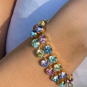 Armband med dubbla rader kristaller Rainbow  - Armband i guldpläterad mässing. Egen design. Två rader med kristaller. Light Sapphire, Jonquil, Light Rose, Chrysolite och Violett. Ss39, 8mm stora kristaller. Längd 24cm inkl lås och förlängningskedja.   Jag skickar endast spårbart, samfraktar. Fast pris. Besök gärna mina övriga annonser.  Till mina smycken använder jag kristaller från Preciosa, Aurora och Swarowski.