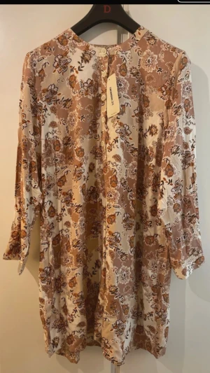 Mönstrad Tunika - Mönstrad tunika med knäppning från turkiska märket LC Waikiki. Passar väldigt bra med blå/mörkblå jeans! Tunikan kan även bäras som en mini-klänning. Aldrig använd och ska säljas på grund av fel storlek. Det står att storleken är 46 enligt turkisk standard, men jag bedömer att den även passar storlek 40-44, med skillnad i hur ”flowig” man vill ha den. Väldigt mjukt material.