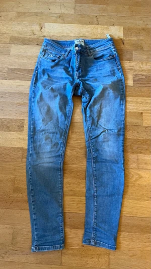 Skinny jeans - Snygga blå skinny jeans med hög midja och klassisk femficksdesign. Jeansen har dragkedjegylf och knapp framtill samt ljus tvätt med subtila slitningar. Tillverkade i stretchigt denimtyg för skön passform.