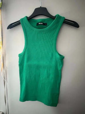 Grön ribbad linnetopp från Bik Bok - Snygg grön ribbad linnetopp från Bik Bok. Toppen är ärmlös med rund halsringning och har en tight passform som framhäver figuren. Perfekt för varma dagar eller som layering-piece. Enkel och stilren design som passar till det mesta.
