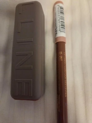 Maybelline brun läppenna och läppstift - Säljer ett snyggt brunt läppstift från Maybelline tillsammans med matchande läppenna i nyansen 05 Onni. Läppstiftet har en matt finish och kommer i en stilren, beige hylsa med tydlig logga. Läppennan har träkropp och ger en exakt applicering. Endast testad på handen en gång.