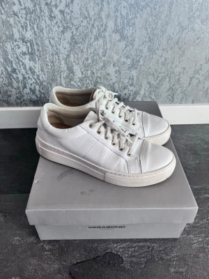Vita sneakers från Vagabond - Stilrena vita sneakers från Vagabond med lågt skaft och klassisk snörning. Skorna har en chunky sula och är tillverkade i slätt läder med metallfärgade öljetter. Perfekta för en clean och modern look.